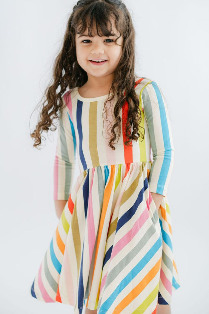 Young girl wearing a colorful striped dress against a white background