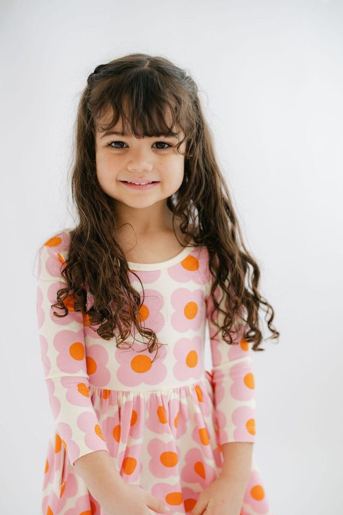 Young girl wearing a dress with pin and orange flowers against a white background