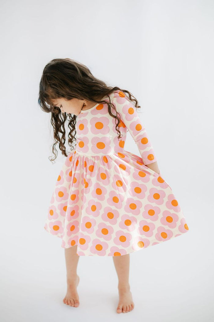 Child wearing a dress with pink and orange flowers on a white background