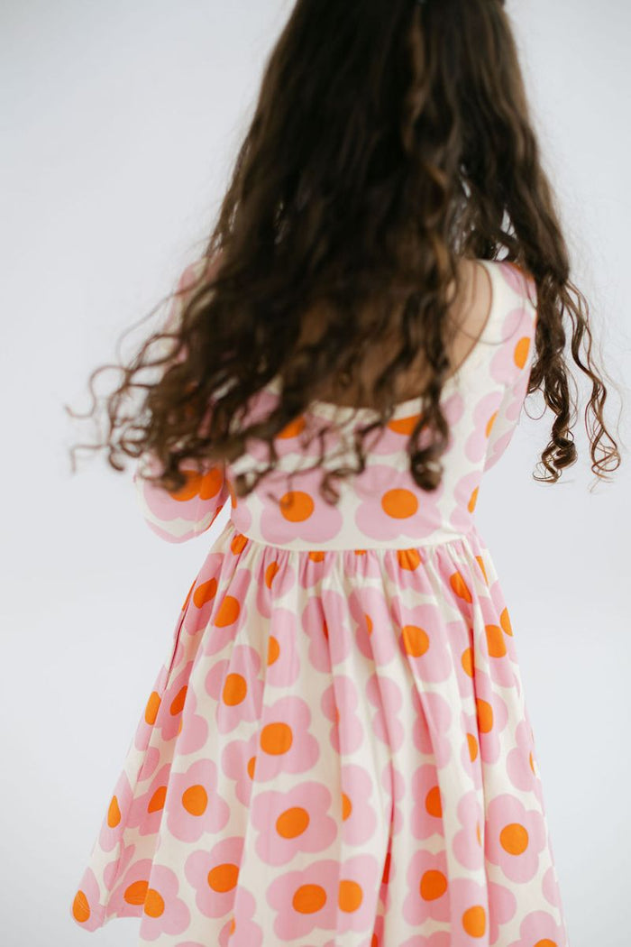 Child wearing a dress with pink and orange flowers on a white background