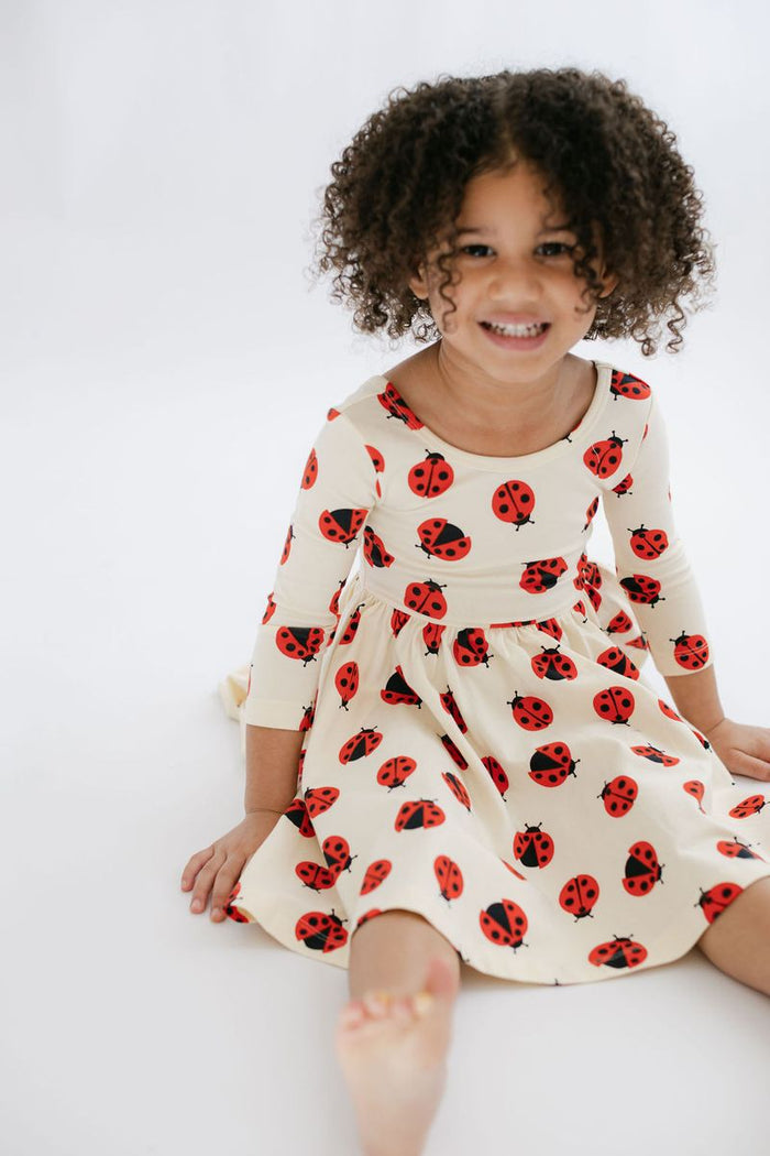 Child wearing a dress with ladybug pattern on a white background