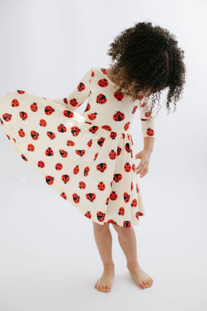 Child wearing a dress with ladybug pattern on a white background