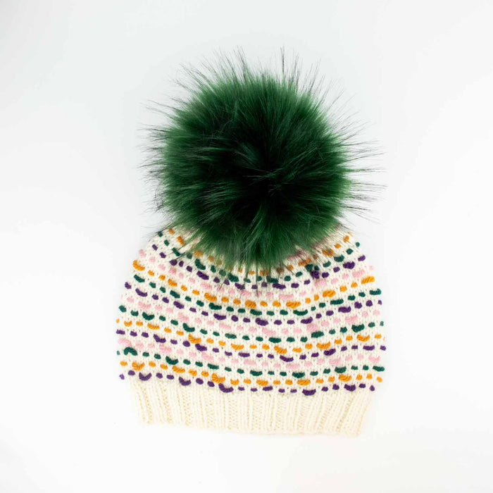 Colorwork knitted hat in cream with pink, green, purple, and ochre stitches topped with a Forest Green 6-inch faux fur pom pom on a white background