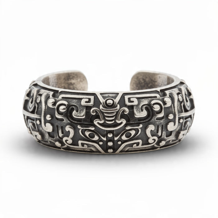 Antique oxidized silver open cuff ring with intricate taotie tribal carvings on pure white background, detailed mythological motif with blackened recesses, adjustable statement band