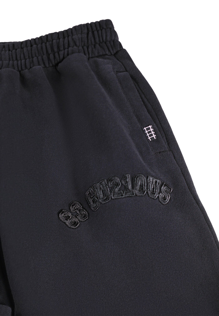 Black sweatpants with embroidered text on a white background