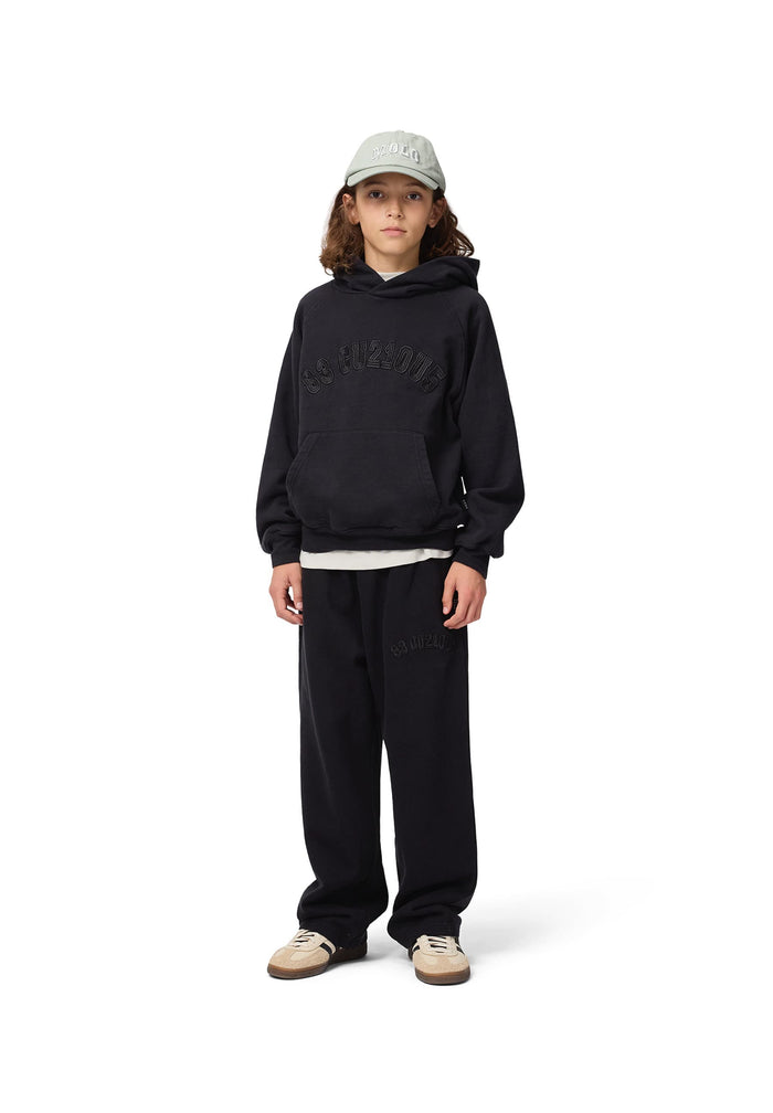 Person wearing a black hoodie and pants with a white cap on a white background