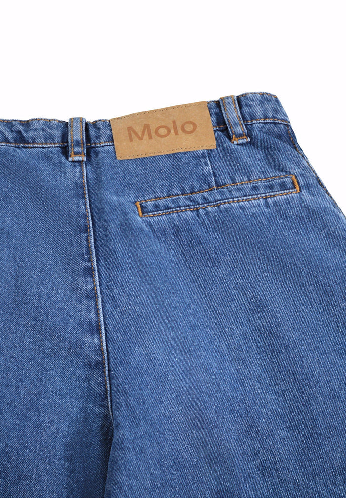 Close-up of blue jeans with a visible brand label on a white background