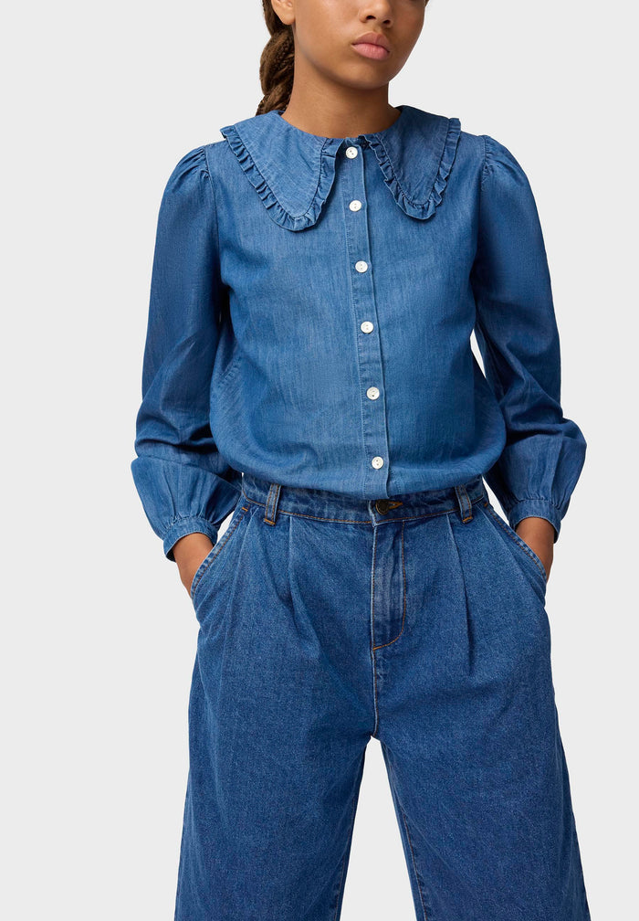 Person wearing a blue denim outfit with a white background