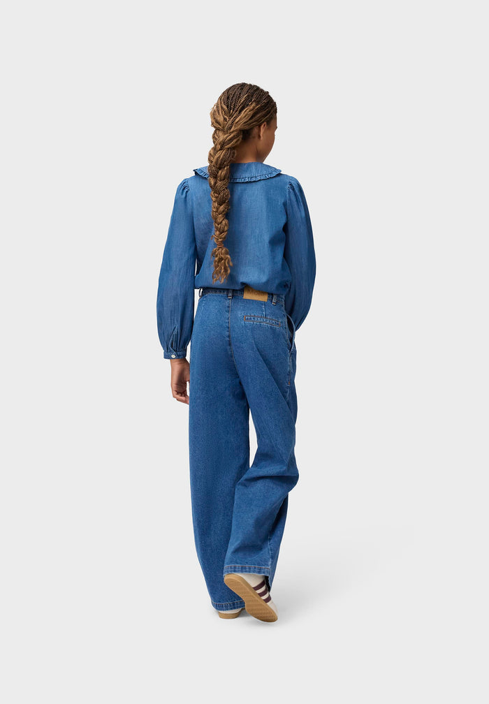 Person wearing a blue denim outfit on a white background