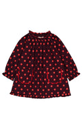 A long-sleeve children's dress with a red and polka dot pattern, featuring a gathered smocked neckline, ruffled cuffs, and two front patch pockets, shown flat on a white background.