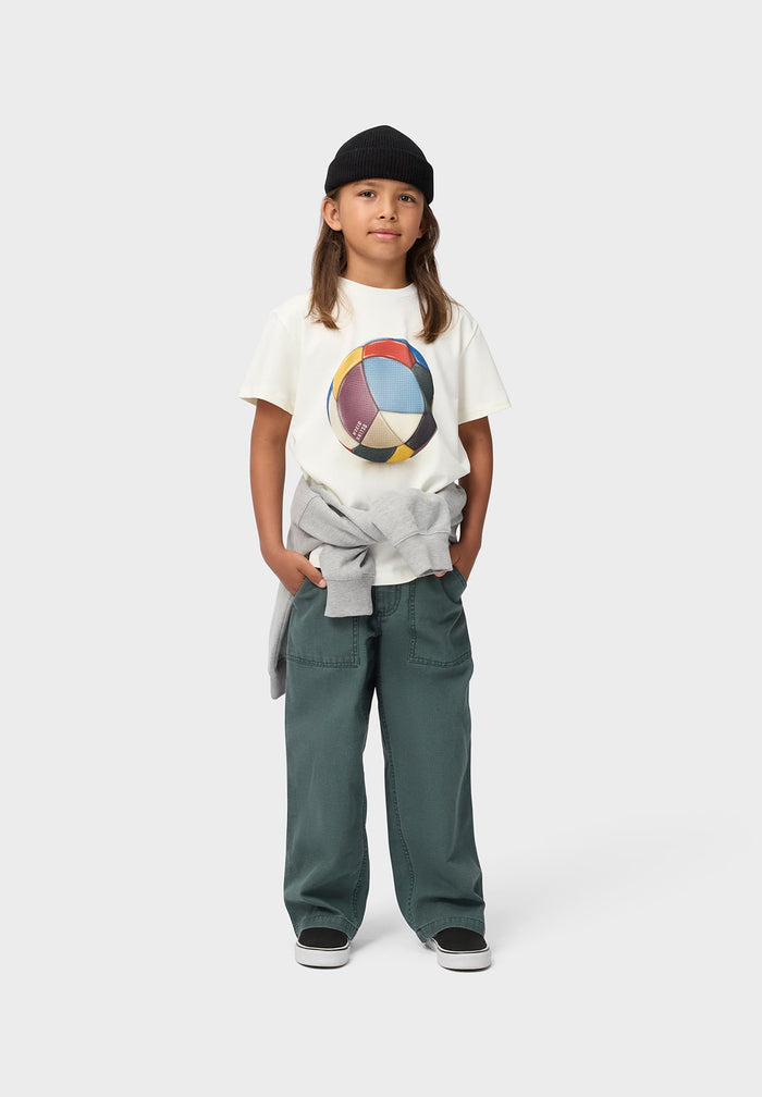 Child wearing a white t-shirt with a colorful graphic and green pants on a white background