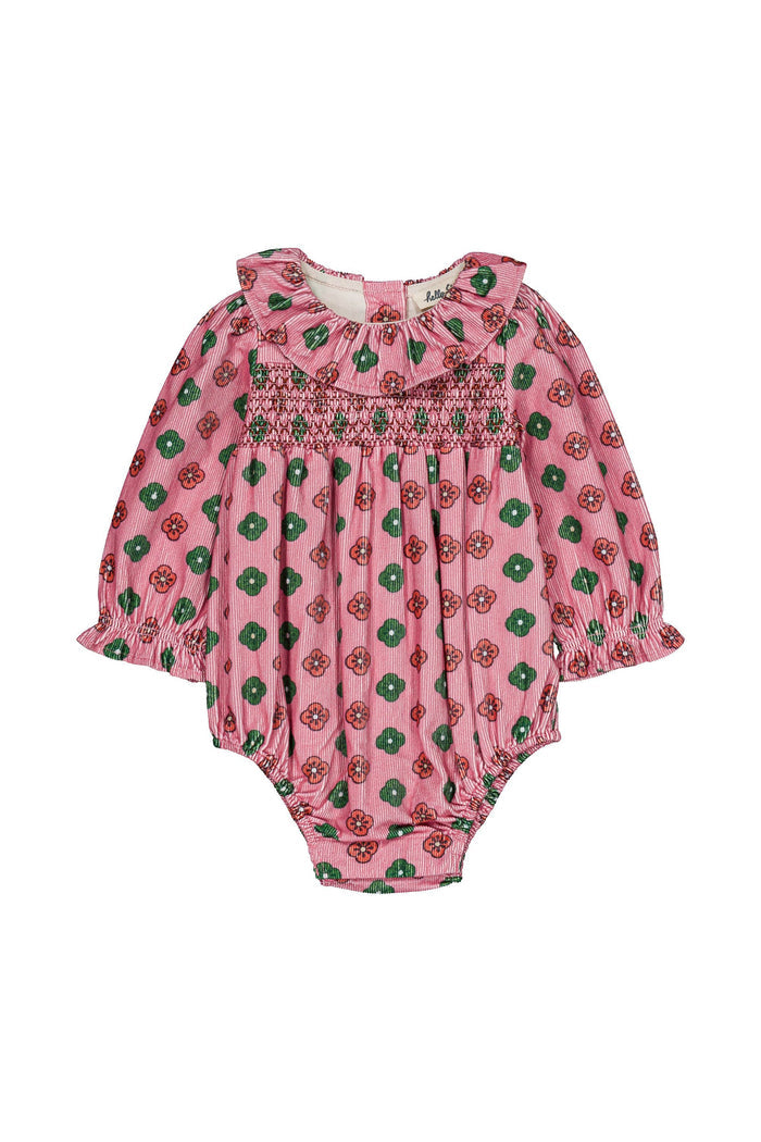A pink baby romper with a green and red floral pattern, featuring long sleeves, a ruffled collar, and smocked detailing across the chest.