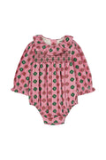 A pink baby romper with a green and red floral pattern, featuring long sleeves, a ruffled collar, and smocked detailing across the chest.