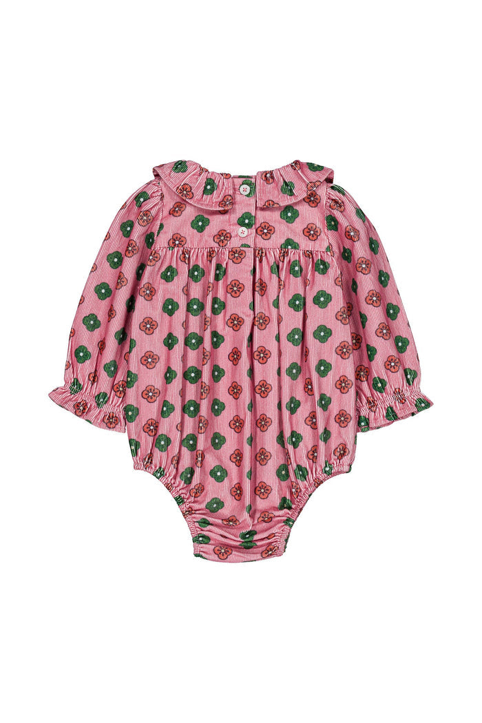 A pink baby romper with a green and red floral pattern, featuring long ruffled sleeves and a ruffled neckline, laid flat on a white background.
