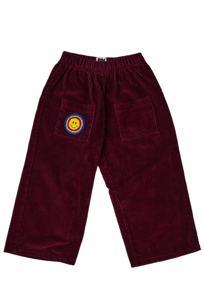 Maroon corduroy pants with a colorful patch on a white background