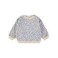 A long-sleeve crewneck sweatshirt for children, featuring a blue hand-drawn dot pattern on a cream-colored base, with ribbed cuffs, hem, and collar, and a chest pocket.