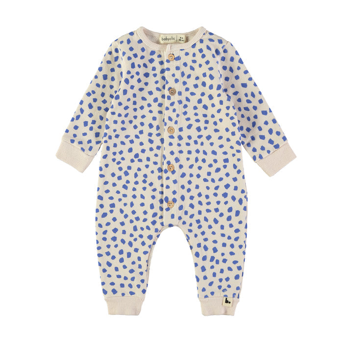 A baby long-sleeve footless romper in cream cotton with a blue spotted pattern, featuring a snap-button front and ribbed cuffs and hem.