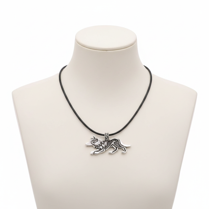 A detailed antique silver wolf pendant with Nordic engravings on a black leather cord, displayed on a minimalist white mannequin.