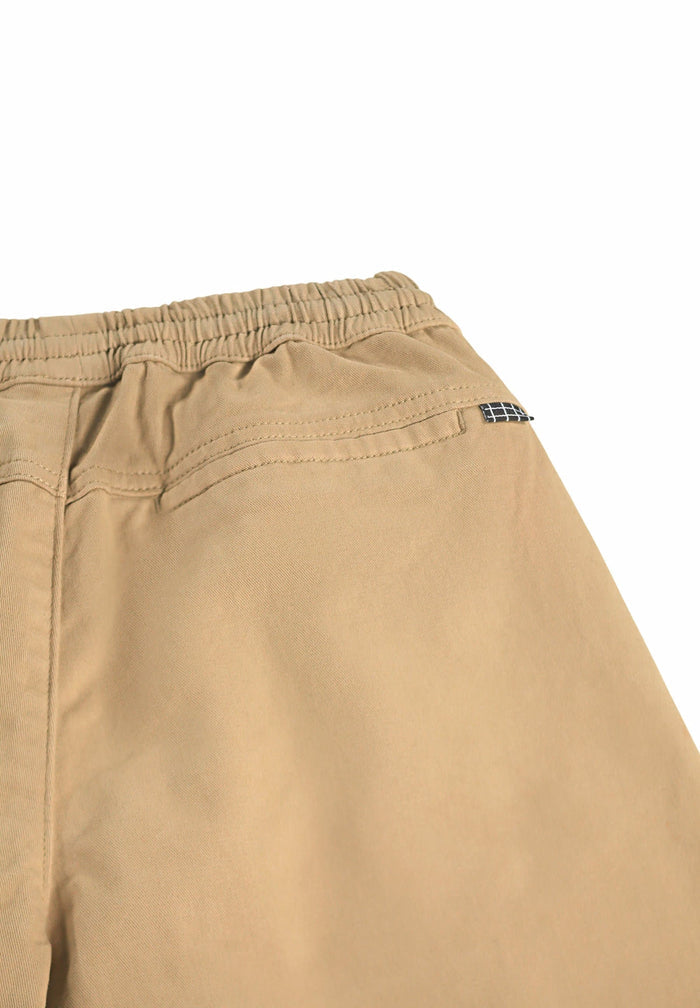 Close-up of beige pants with a brand logo on a white background