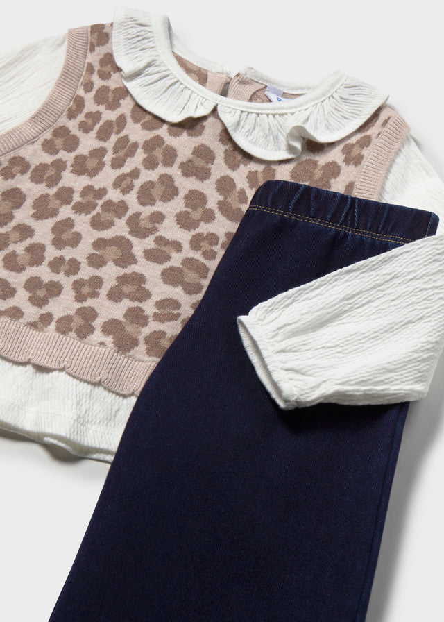 Children's clothing including a leopard print sweater, navy pants, and white shirt on a light background