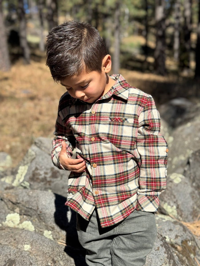 Child wearing a plaid shirt standing on rocks with a natural background