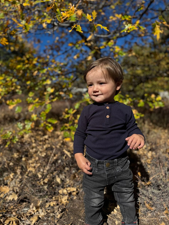 child wearing navy henley onesie