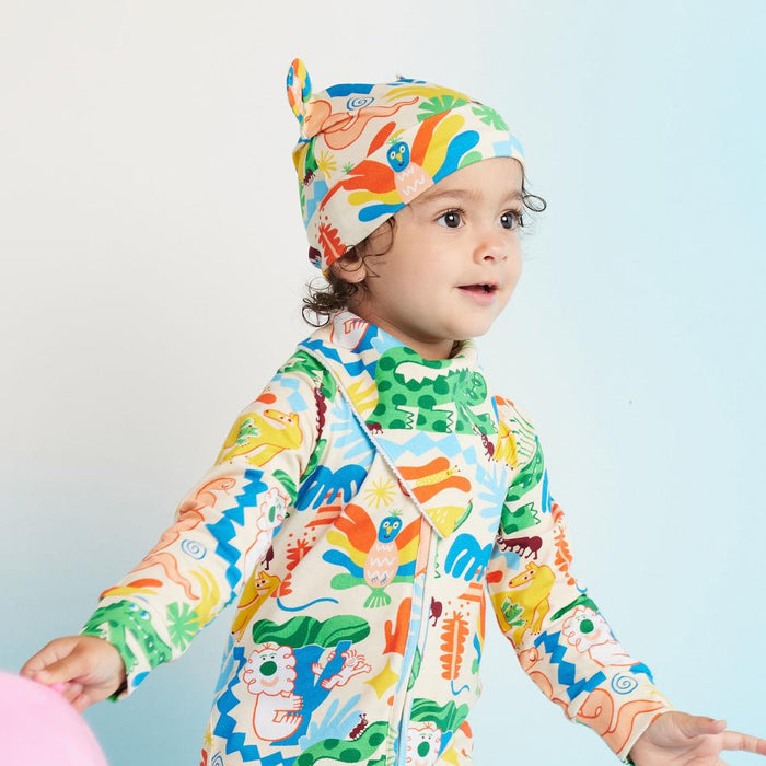 Child wearing a colorful outfit and hat on a light blue background