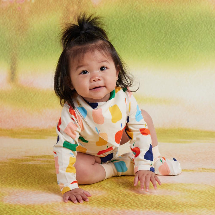 Baby wearing a colorful outfit sitting on a patterned blanket