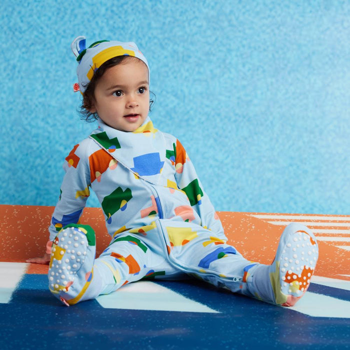 Child wearing a colorful onesie with vehicle patterns on a blue and orange striped surface.