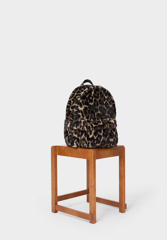 Leopard print backpack on a wooden stool against a white background