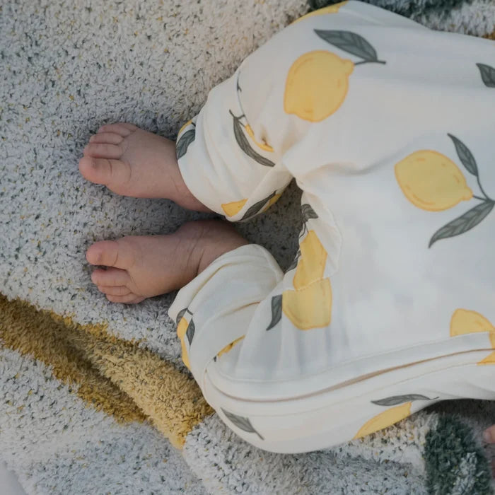 Child wearing a onesie with lemon pattern on a textured surface