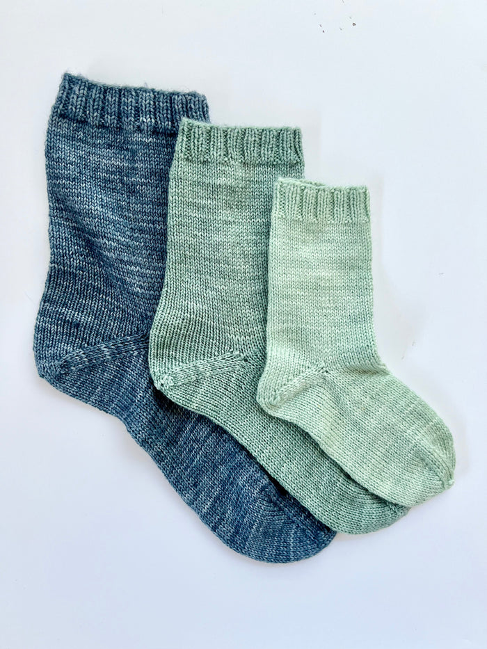 Three Base Doodle Top-Down Socks in blue and green fingering weight yarn