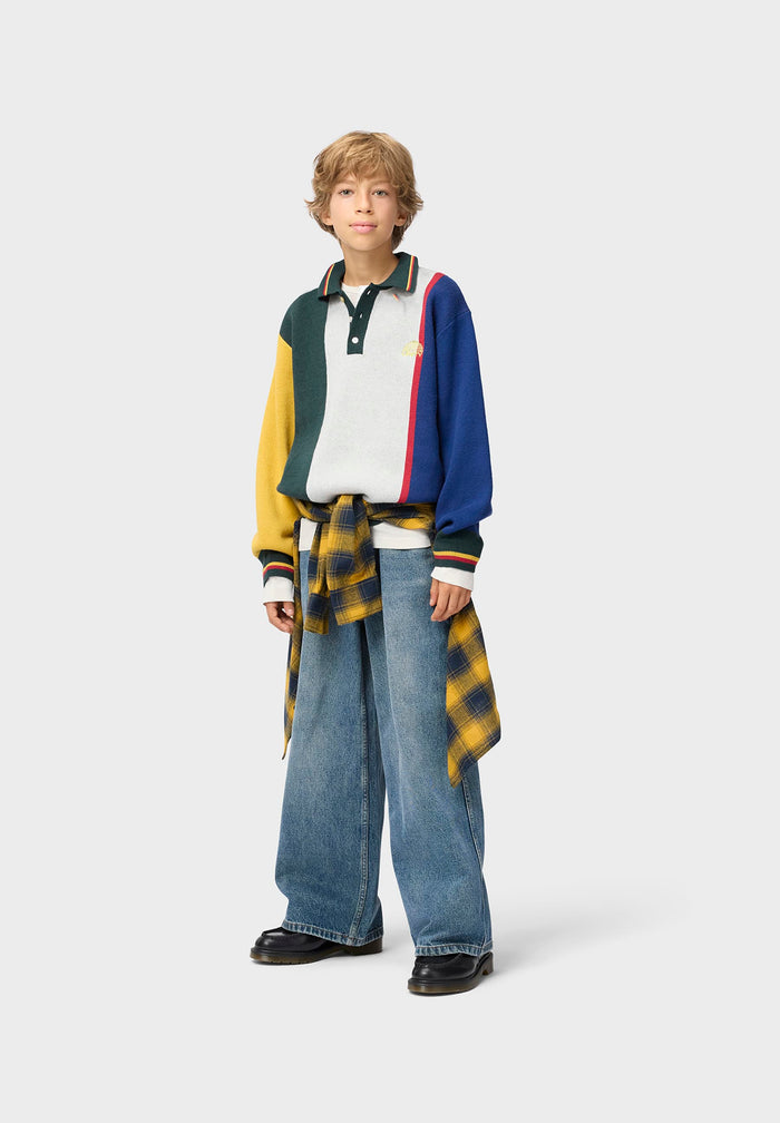 Person wearing a colorful polo sweater and jeans on a white background