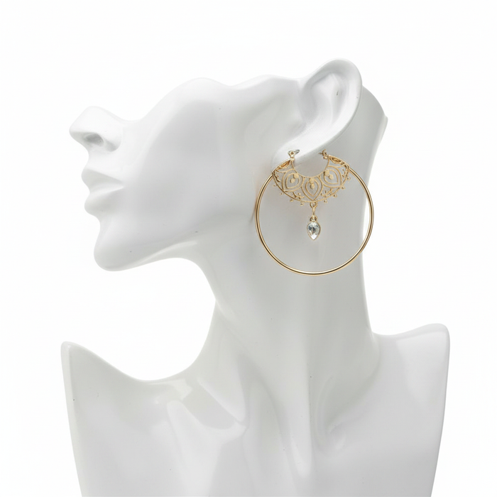 Large gold-plated hoop earring featuring an intricate mandala filigree design and a dangling clear crystal teardrop on a white mannequin profile.