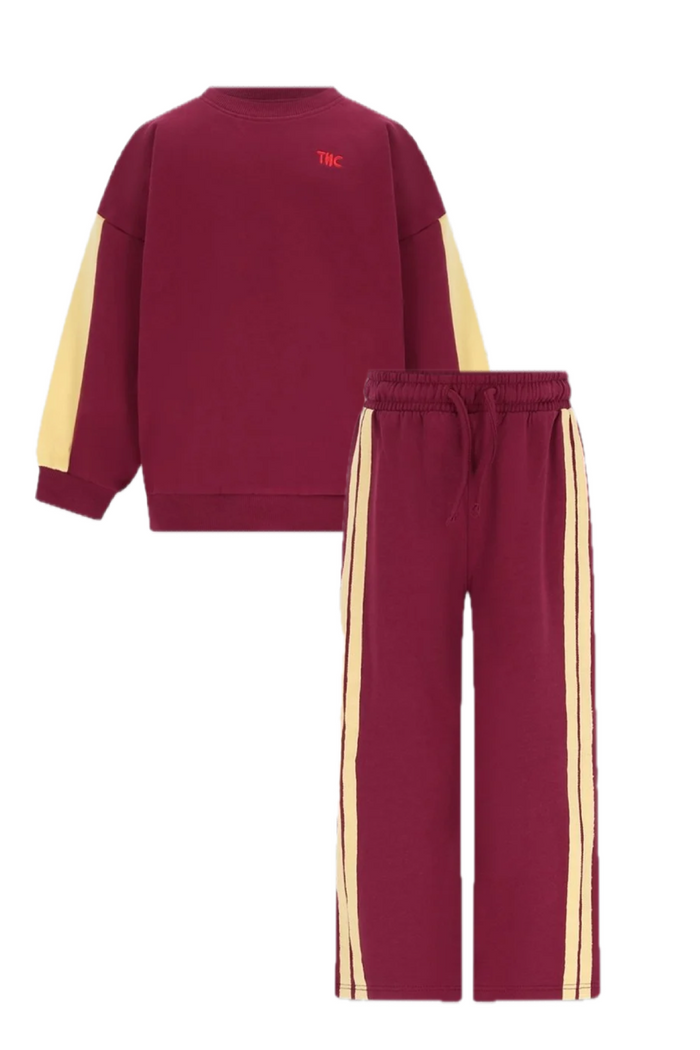 burgundy wide leg sweatpants with drawstring, 2 pale yellow side stripes and matching burgundy sweatshirt with yellow colorblocked sleeves on white background