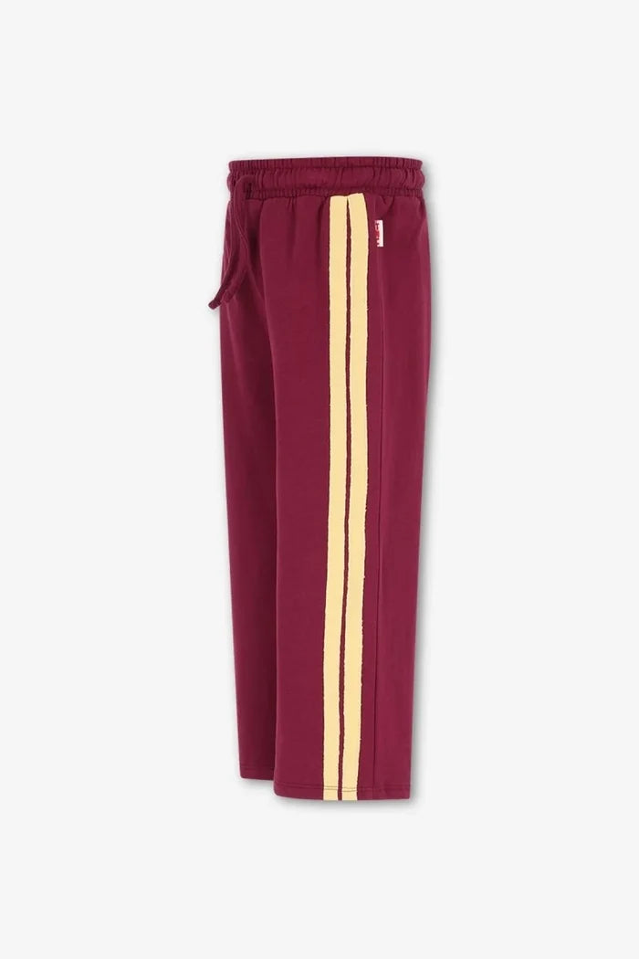 side view burgundy straight leg sweatpants with  drawstring and 2 pale yellow side stripes on white background