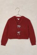 Red cardigan on a hanger against a beige background