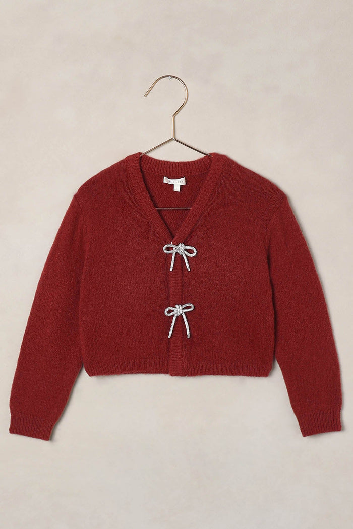 Red cardigan on a hanger against a beige background