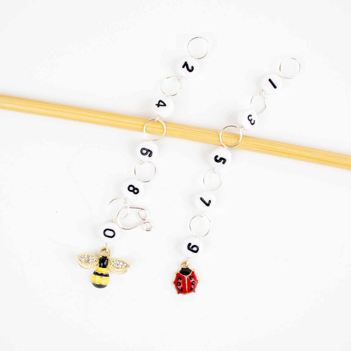 Two straight chain row counters on bamboo needle with enamel bee charm for even numbers and enamel ladybug charm for odd numbers
