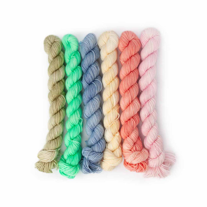 Six mini yarn skeins in bug-inspired pastel colors: sage, mint, periwinkle, cream, coral, and pink