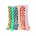 Six mini yarn skeins in bug-inspired pastel colors: sage, mint, periwinkle, cream, coral, and pink