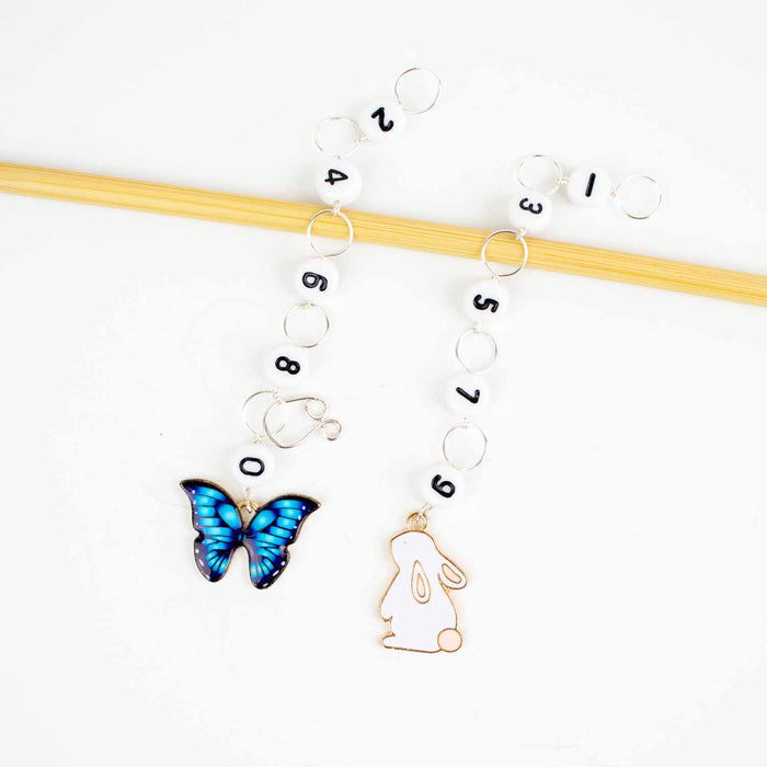 Two straight chain row counters on bamboo needle with blue enamel butterfly charm for even numbers and white enamel bunny charm for odd numbers