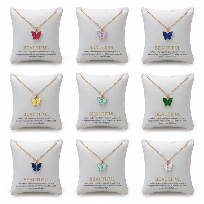 Multiple gold chain necklaces with colorful butterfly charms displayed on elegant white padded jewelry pillows