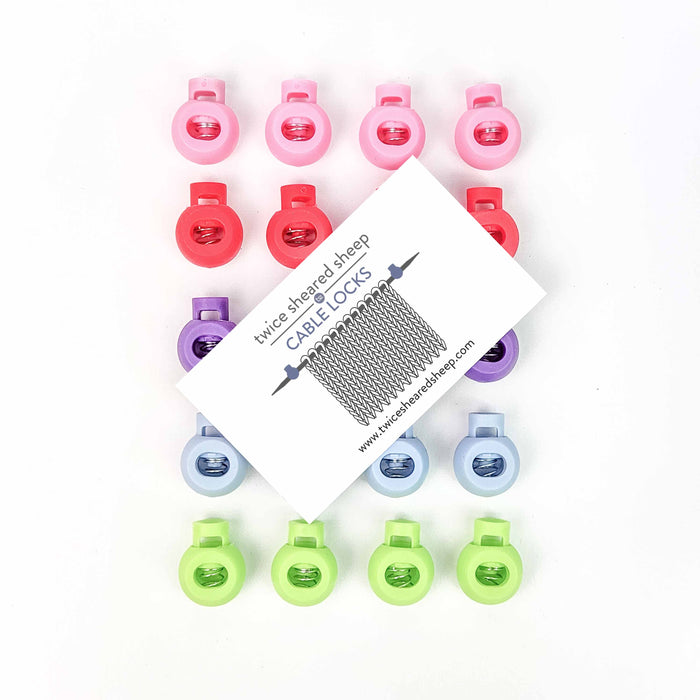 Flat lay of twenty Cable Lock circular needle cord stops arranged in four rows of five, shown in pink, red, purple, blue, and green alongside the Twice Sheared Sheep Cable Locks product card