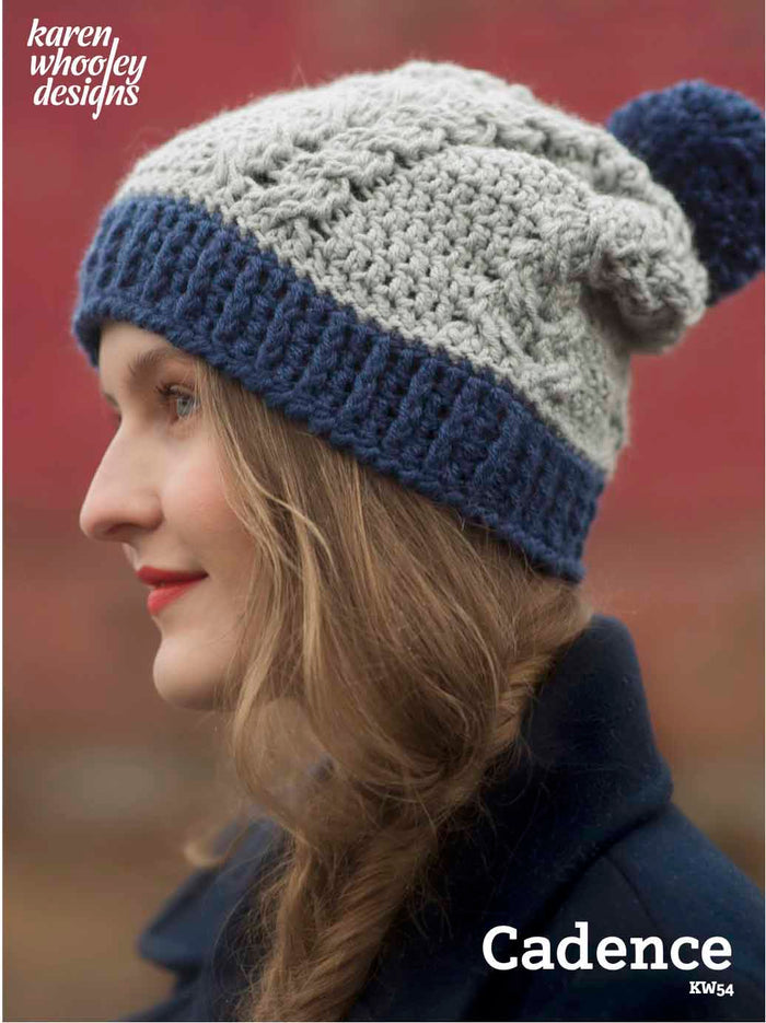 Side profile of woman wearing navy and gray textured crochet slouchy hat with pom-pom
