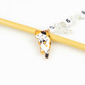 Close-up of the Calico Cat chain row counter charm — an enamel calico cat with orange, black, and white patches hanging from a bamboo knitting needle, with numbered white beads (0 through 9) linked by silver wire rings