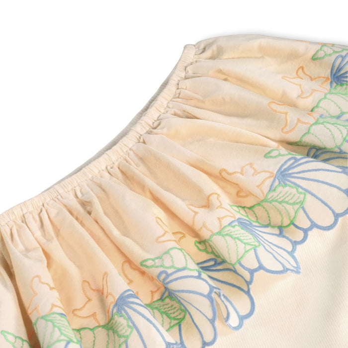 close-up of ruffle shoulder with embroidered seashells detail