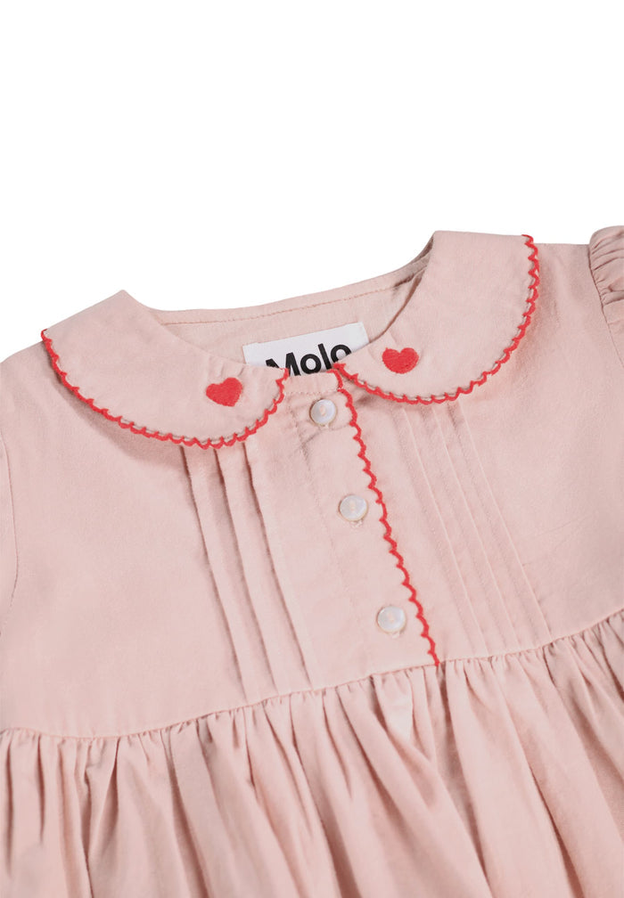 Pink dress with red trim and heart details on a white background