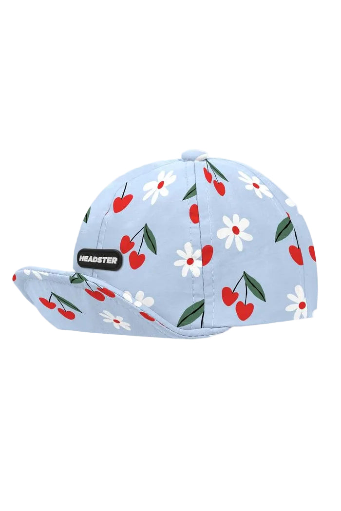 Light blue cap with cherry and flower pattern on a white background