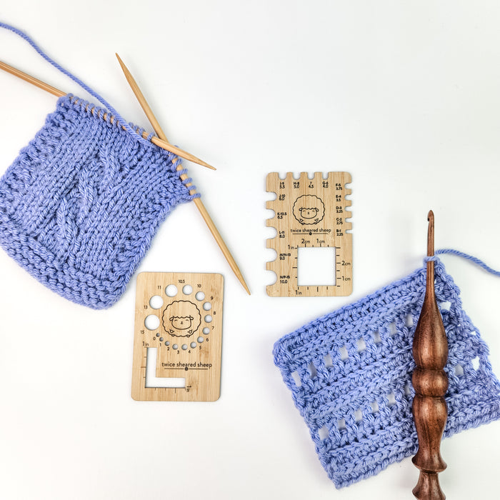 Two wooden gauge tools by Twice Sheared Sheep with blue knitting and crochet swatches and wooden crochet hook